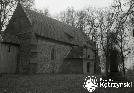 Gudniki, elewacja południowa kościoła z pomnikiem upamiętniającym poległych mieszkańców wsi w latach 1914-1918 – 1999r.