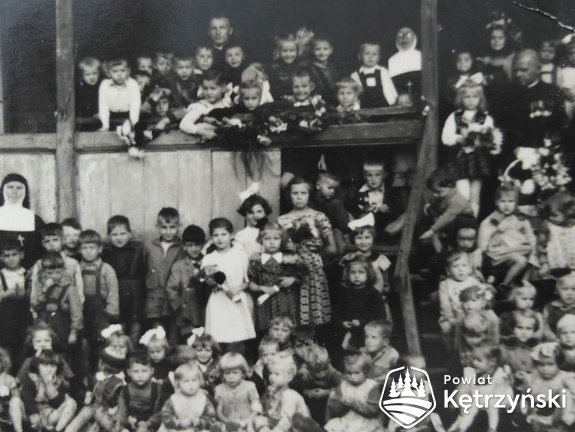 Jubileusz 60. urodzin ks. Rajmunda Butrymowicza z grupą dzieci na schodach plebanii parafii św. Jerzego – 1956r.    