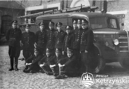 Strażacy straży pożarnej na terenie cukrowni przy samochodzie gaśniczym firmy Bedford - I połowa lat 50.